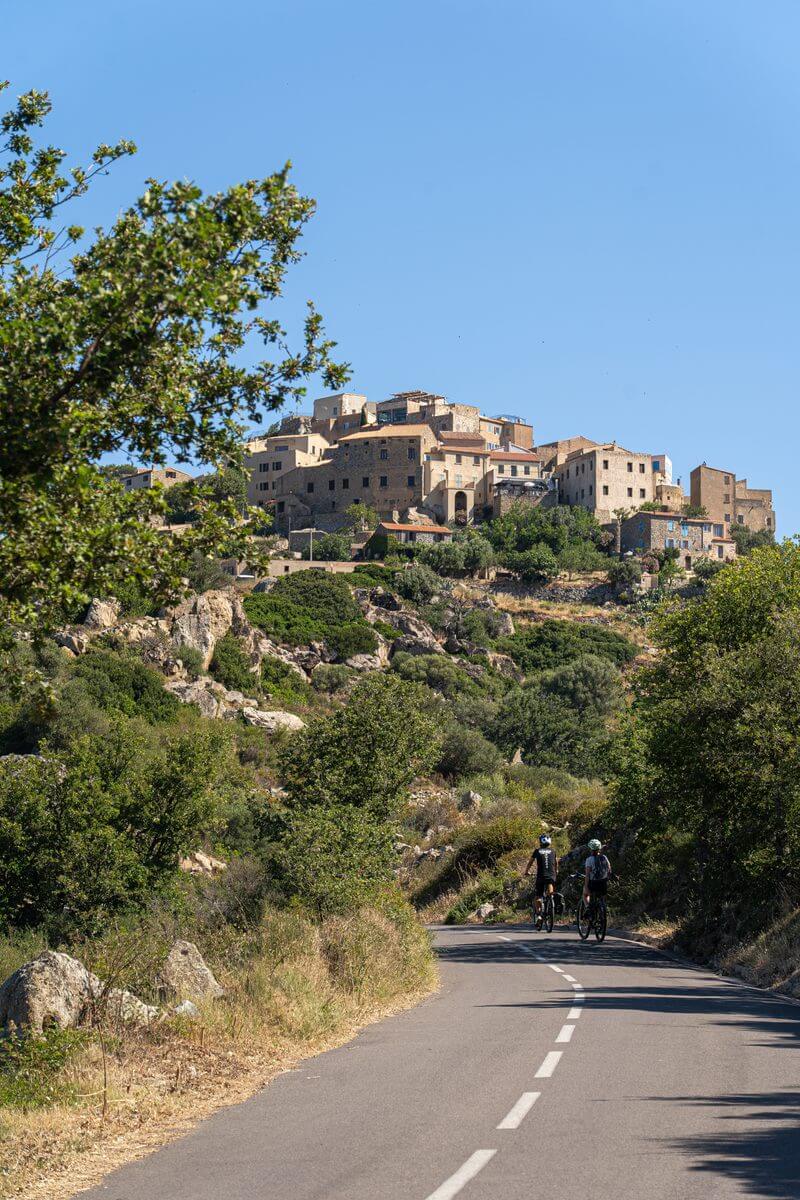Photo de deux cyclistes en route pour le village de Sant' Antonino en fond