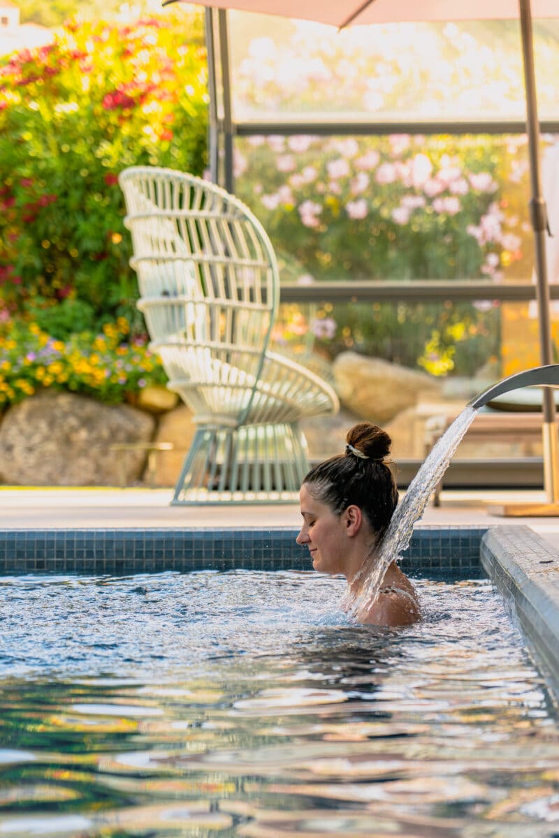 femme profitant d'une cascade d'eau dans une piscine du spa